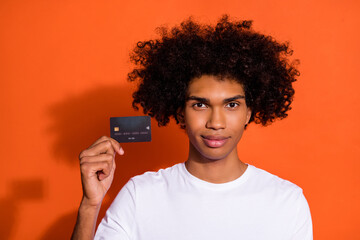 Photo of attractive handsome guy dressed white shirt showing you credit card isolated orange color...
