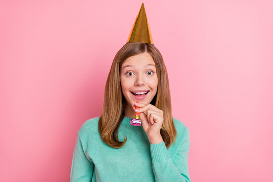 Photo of impressed school girl dressed teal pullover birthday cone blowing whistle isolated pink color background