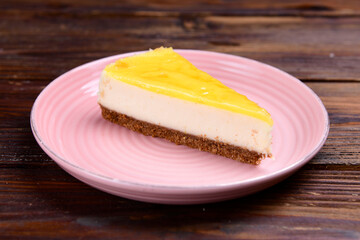 Lemon cheesecake slice on plate on wooden background