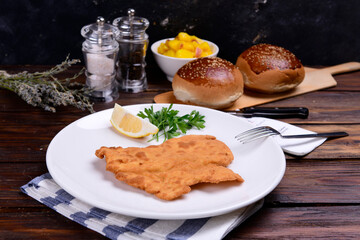 chicken schnitzel and bread on wooden table