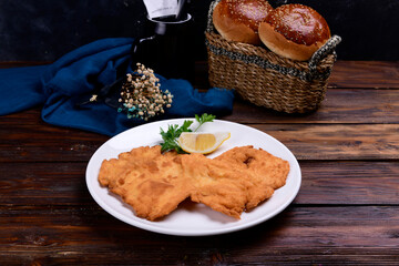 chicken schnitzel and bread on wooden table