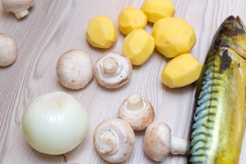 Raw fresh champignons and mackerel fish on a white wooden table.