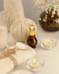 Wellbeing still life with spa accessories, serum, candles and towel on a white table. Wellness and skin care treatment. Spa relax massage procedure. Concept of me time and no depression. Soft focus