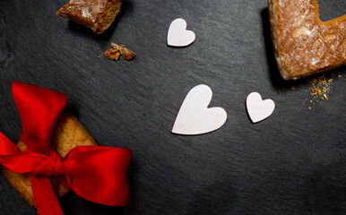 A piece of cookies and cookie wrapped with red ribbon and white hearts on black stone plate. Love valentine concept. Flat lay