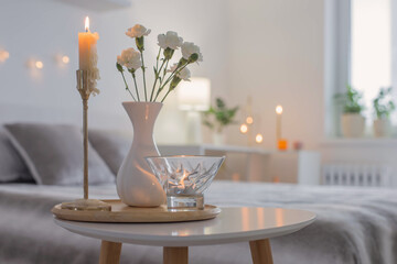 white flowers in vase on table in bedroom