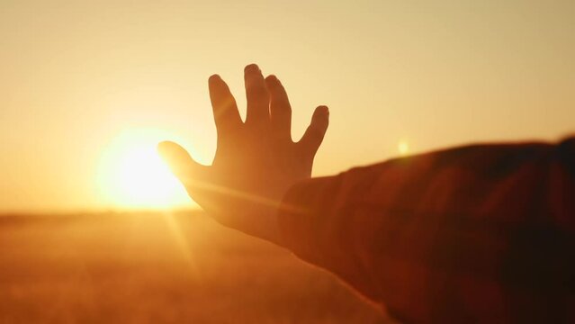 hand reaches for the sun. religion life freedom concept. girl pulls her hand to the sun at sunset close-up lifestyle nature energy. religion work on oneself concept
