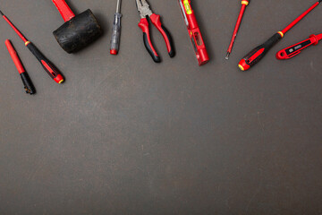 Black and red tools on textured dark grey background. Composition with free space for text. Flat lay, top view, copy space
