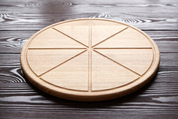 Round pizza cutting board with slice grooves on wooden table