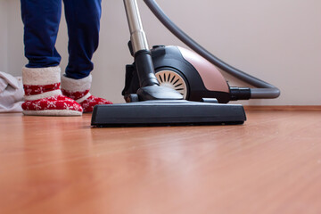 Woman using vacuum cleaner to cleaning parquet floor.