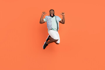 Fototapeta na wymiar Photo of amazed afro guy wear denim vest jumping high pointing himself isolated orange color background