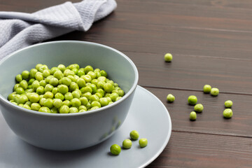 Fresh green peas in gray bowl.