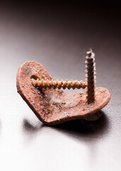 metal angle bracket with corrosive rust and deteriorated screws, grayish background