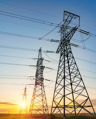 high voltage power lines in the field against the backdrop of a bright and colorful sunset or dawn
