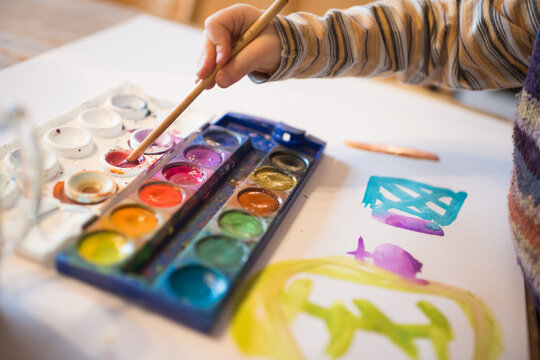 Kinderhand mit Pinsel und Wasserfarbenkasten