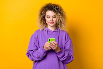 Photo of young girl type sms use smartphone app download repost comment isolated over yellow color background