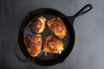 Overhead View of Spice-Rubbed Chicken Thighs in a Cast Iron Skillet: Roasted bone-in skin-on...