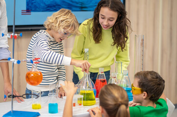 Boy lowering pipette into flask and children watching