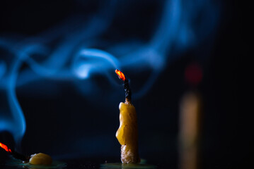 Burning candle, smoke on a dark background.