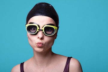 woman swimmer, in a swimming cap, glasses and a swimsuit, blue background