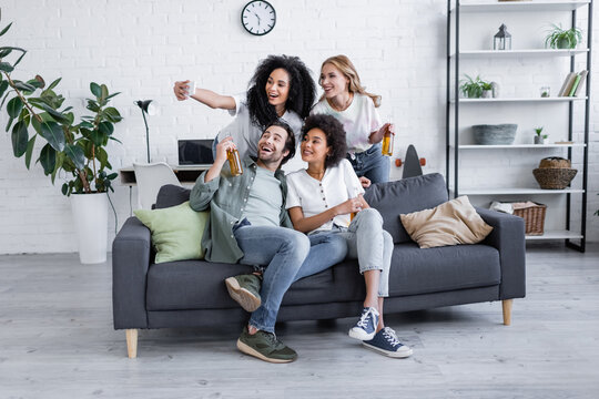 happy african american woman taking selfie with friends in living room.
