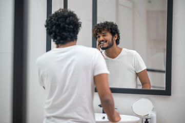 Pleased young male admiring his good looks