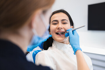 Pretty brunette woman at the dentist appointment. Female patient treats her teeth in a dental clinic