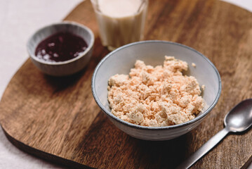 Homemade melted cheese curd served with baked milk and jam on wooden cutboard. Healthy breakfast. Haze effect. Selective focus