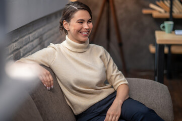 Fototapeta premium Happy lady seated on the sofa indoors