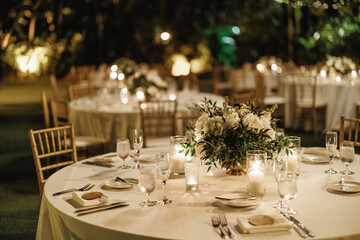 Served table for dinner on the wedding party at the hotel restaurant Table set up for a special event with roses and greenery outdoors Wedding table setting decorated with bouquets of white roses 