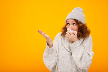 Woman with a cold blowing her runny nose with tissue holding your product. Portrait of beautiful...
