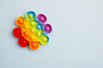 Top view of colorful anti stress sensory toy pop it rainbow flower on blue background close up. Creative and funny concepts of children toys. Popular toy. Trend toy 2021-2022 year. Copy space