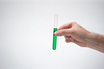 Medical test tube containing a green liquid held in hand by Caucasian male. Close up studio shot, isolated on white background