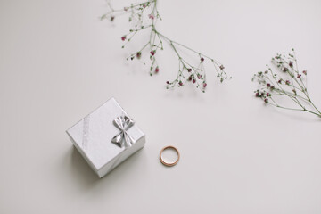 Box with golden engagement ring on flowers background, top view. Wedding, Marriage proposal concept