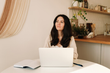 A business woman freelancer in casual clothes works online remotely using a laptop, mobile phone and technology while sitting in an indoor home office. Online education. Selective focus