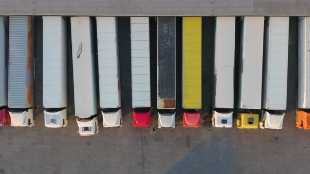 Aerial top down view of semi-trailers trucks standing at a warehouse ramps for loading and unloading goods