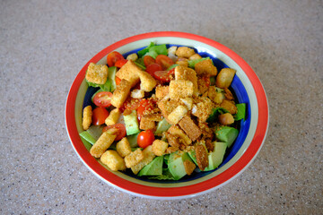 Fresh salad with lettuce, tomato, avocado and croutons in a colorful bowl