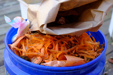 Bin full with carrot peelings and kitchen scraps ready to be composted