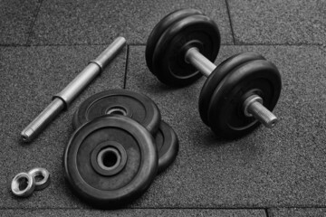Naklejka na ściany i meble dumbbell and iron plates on the rubber floor in the gym. black and white photography. Bodybuilding equipment. Fitness or bodybuilding concept background.