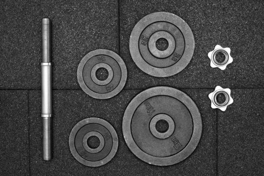 dumbbell and iron plates on the rubber floor in the gym, Flat lay, black and white photography. Bodybuilding equipment. Fitness or bodybuilding concept background.