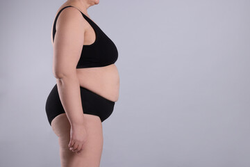 Overweight woman in underwear on grey background, closeup. Space for text