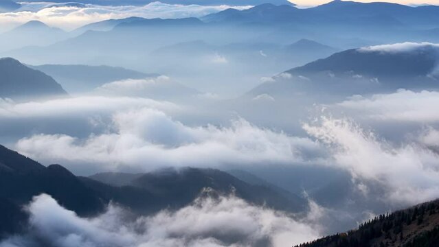 Clouds spill over the tops of the hills in the light of the rising sun, Mystical morning landscape