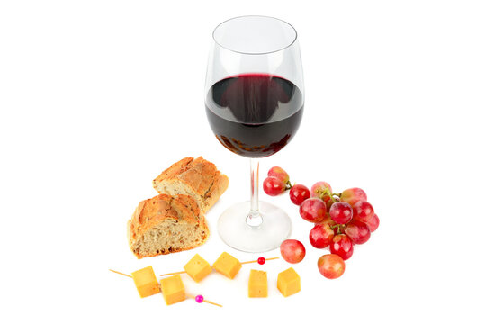 A glass of red wine , bunch of grapes , baguette and cheese isolated on a white.