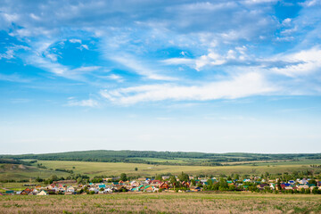 View of the village from the hill. Summer, sky and small houses.