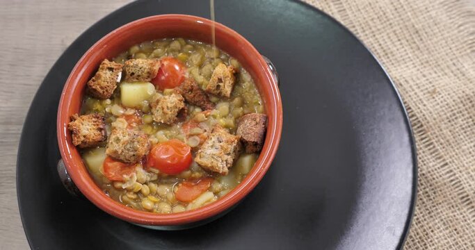 Il cuoco versa l'olio nella zuppa di lenticchie