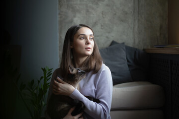 Obraz premium A girl with cat sits by the window