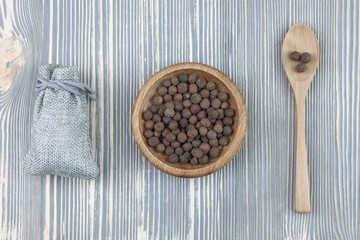 Peppercorns black. Spoon and plate on a wooden table.