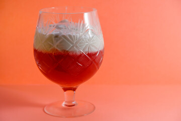 Jelly from redcurrants and sour cream, in vintage crystal glass on a coral-colored background. Copy space. 	