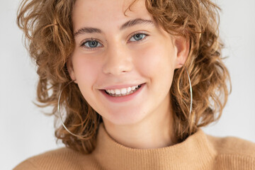 Woman with curly beautiful hair on gray background. Girl with beauty a pleasant smile. Short wavy hairstyle, smiling woman