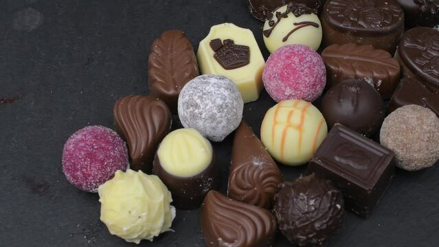 Assorted delicious chocolate pralines. Selection of pralines with milk and dark chocolate on slate rotating tray. Loving chocolate and sweets concept