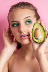 Close up view of gorgeous ginger woman with avocado. Studio shot of excited caucasian girl with healthy food isolated on pink background.